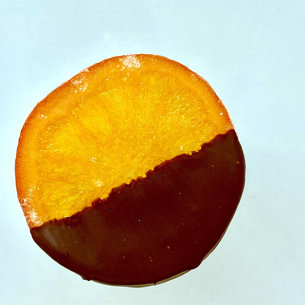 candied orange slice half-dipped in chocolate on a blue background