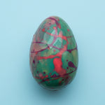 Load image into Gallery viewer, dark chocolate egg shell with colourful pattern on a blue background
