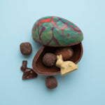 Load image into Gallery viewer, colourful dark chocolate egg shell with caramels, chocolate bunnies and a small chocolate egg

