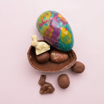 Load image into Gallery viewer, colourful milk chocolate egg shell with caramels, chocolate bunnies and a small chocolate egg
