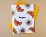 Load image into Gallery viewer, Greeting card with croissants and coffee cups on a white background  with text 'bonjour!' on a yellow envelope
