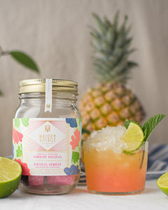 Hawaiian hibiskiss cocktail kit jar with a rock glass with the cocktail, crushed ice, a lemon slice and menta leaves