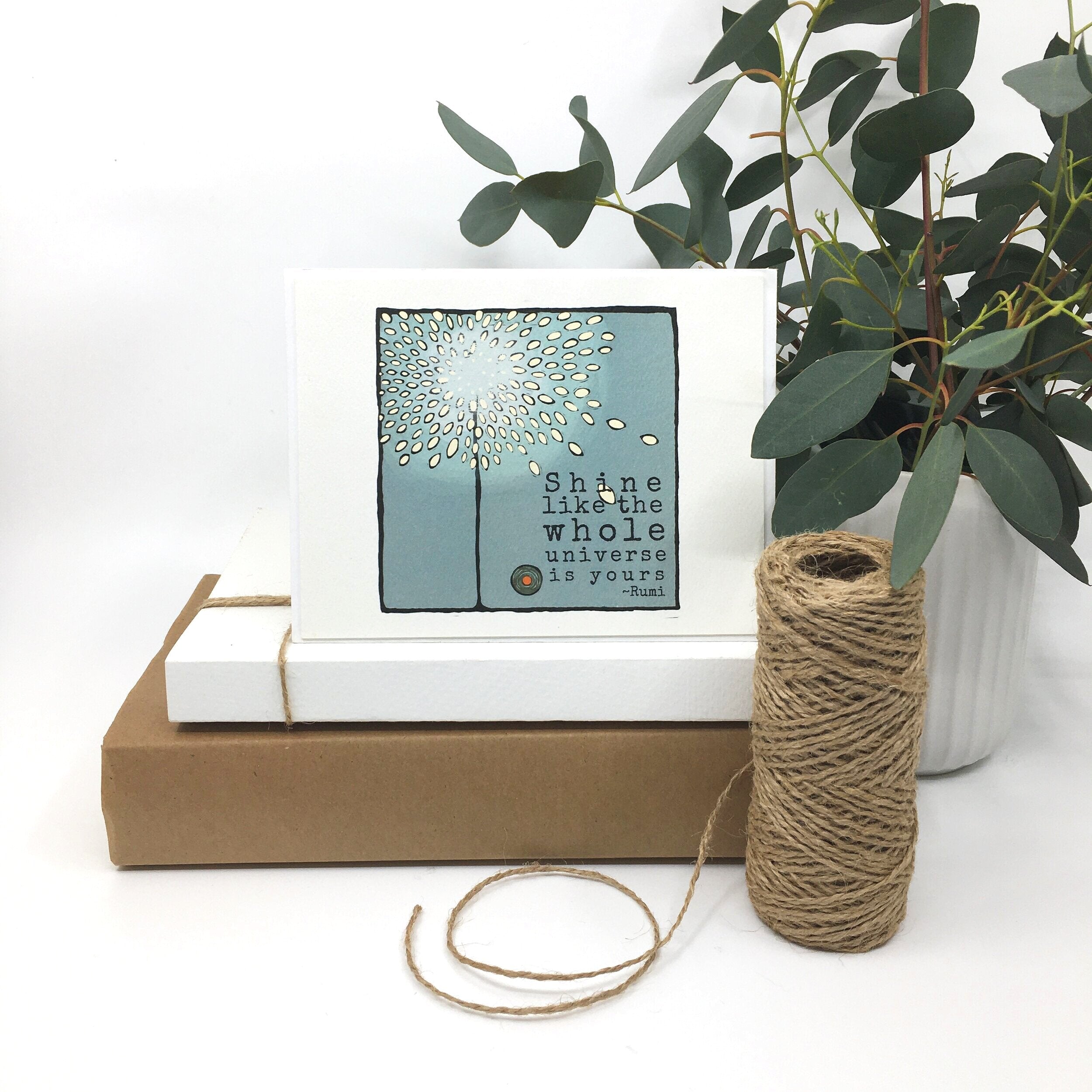 shine like the whole universe quote card sits on two paper boxes besides a roll of twine and a potted plant