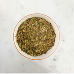 Load image into Gallery viewer, White bowl filled with dried tea leaves on a marble surface
