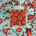 Load image into Gallery viewer, strawberry sumac bar on a bed of strawberry fruit pieces and sumac berries
