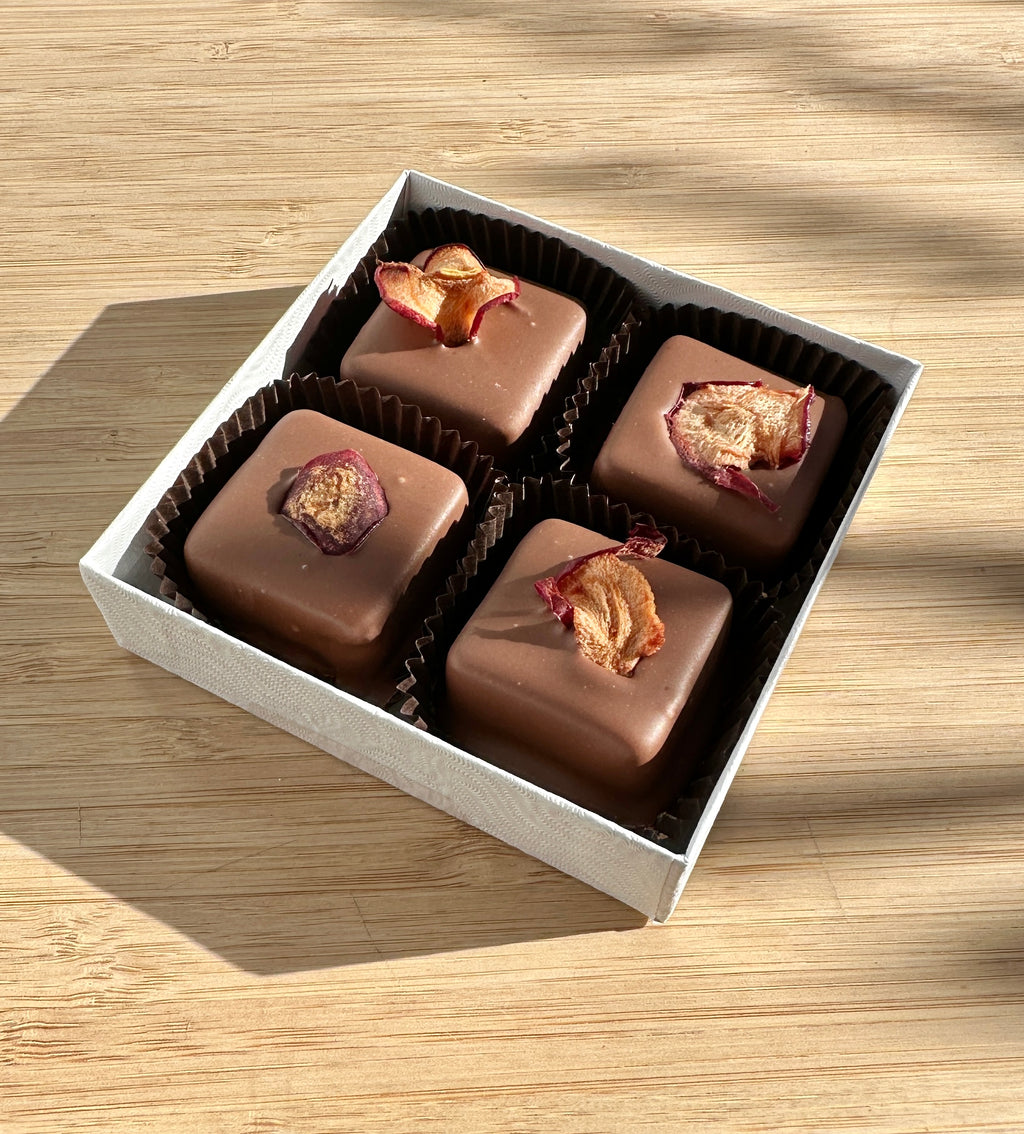 Box of chocolate caramels with pieces of dried apple on a wooden surface