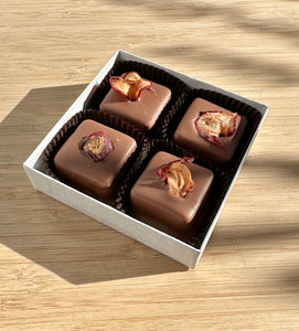 Box of chocolate caramels with pieces of dried apple on a wooden surface