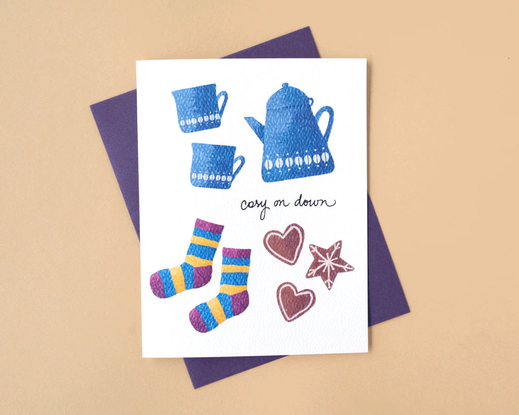 Greeting card with blue teacups, socks, and decorative elements on a beige background