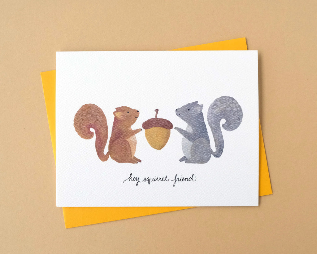 Greeting card with two squirrels and an acorn on a beige background