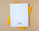 Load image into Gallery viewer, White card back with text on a yellow envelope against a beige background
