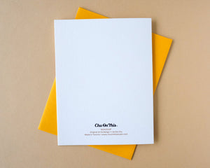 White card back with text on a yellow envelope against a beige background
