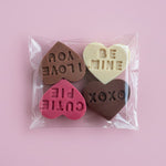 Load image into Gallery viewer, chocolate conversation hearts on a light pink background
