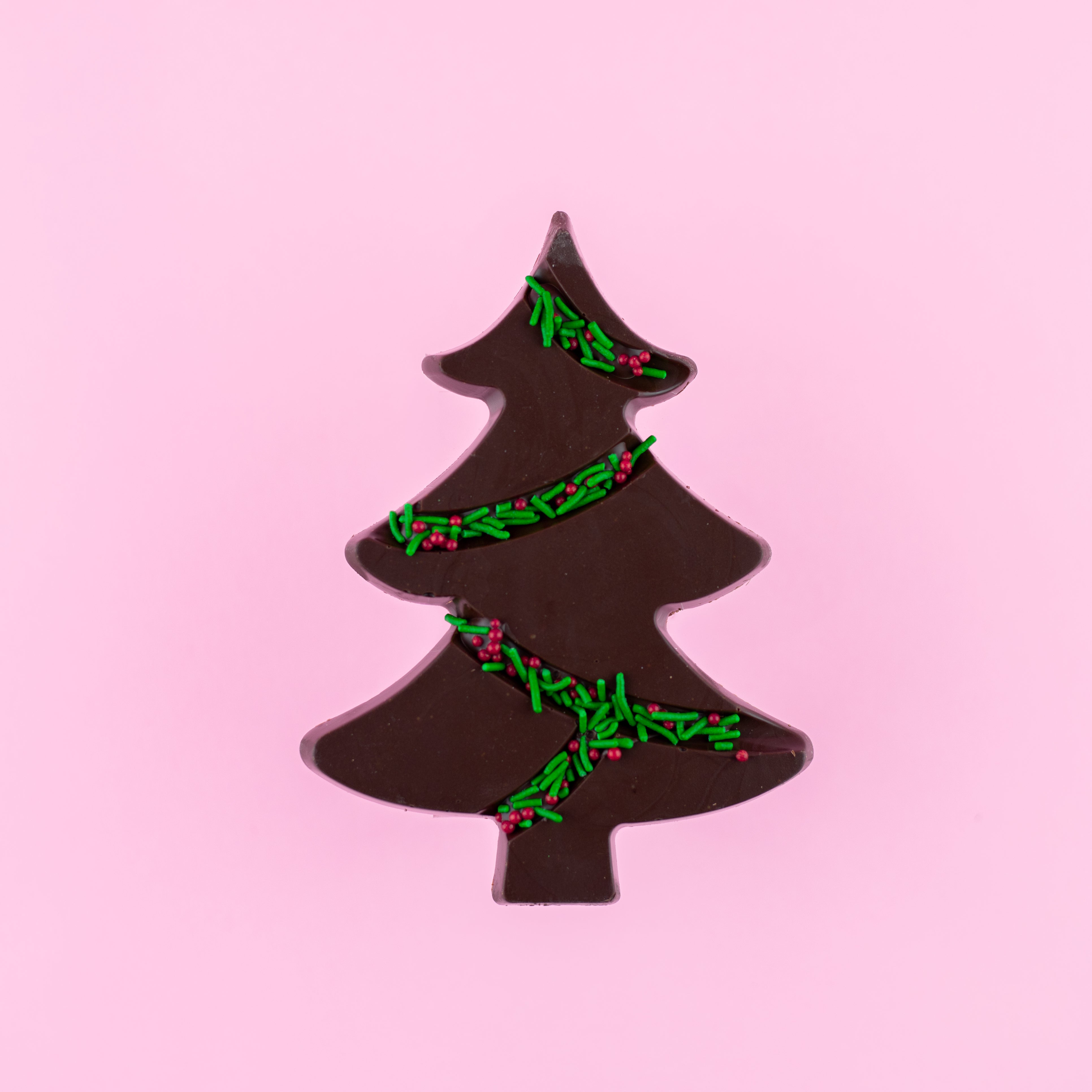 dark chocolate tree with green and red sprinkles on a pink background