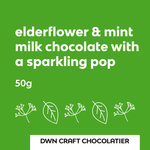 Load image into Gallery viewer, green label that reads "elderflower &amp; mint milk chocolate with a sparkling pop" with outlines of mint leaves and elderfloers

