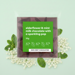 Load image into Gallery viewer, elderflower and mint milk chocolate bar in packaging with a light green background
