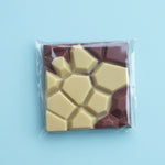 Load image into Gallery viewer, packaged haskap lemon chocolate bar with geometric design on a light blue background
