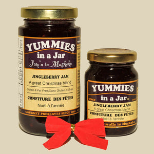 Two jars of Yummies in a Jar Jingleberry Jam with a red bow on a beige background