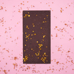 Load image into Gallery viewer, lilac dark chocolate bar with bee pollen sprinkled on a pink background
