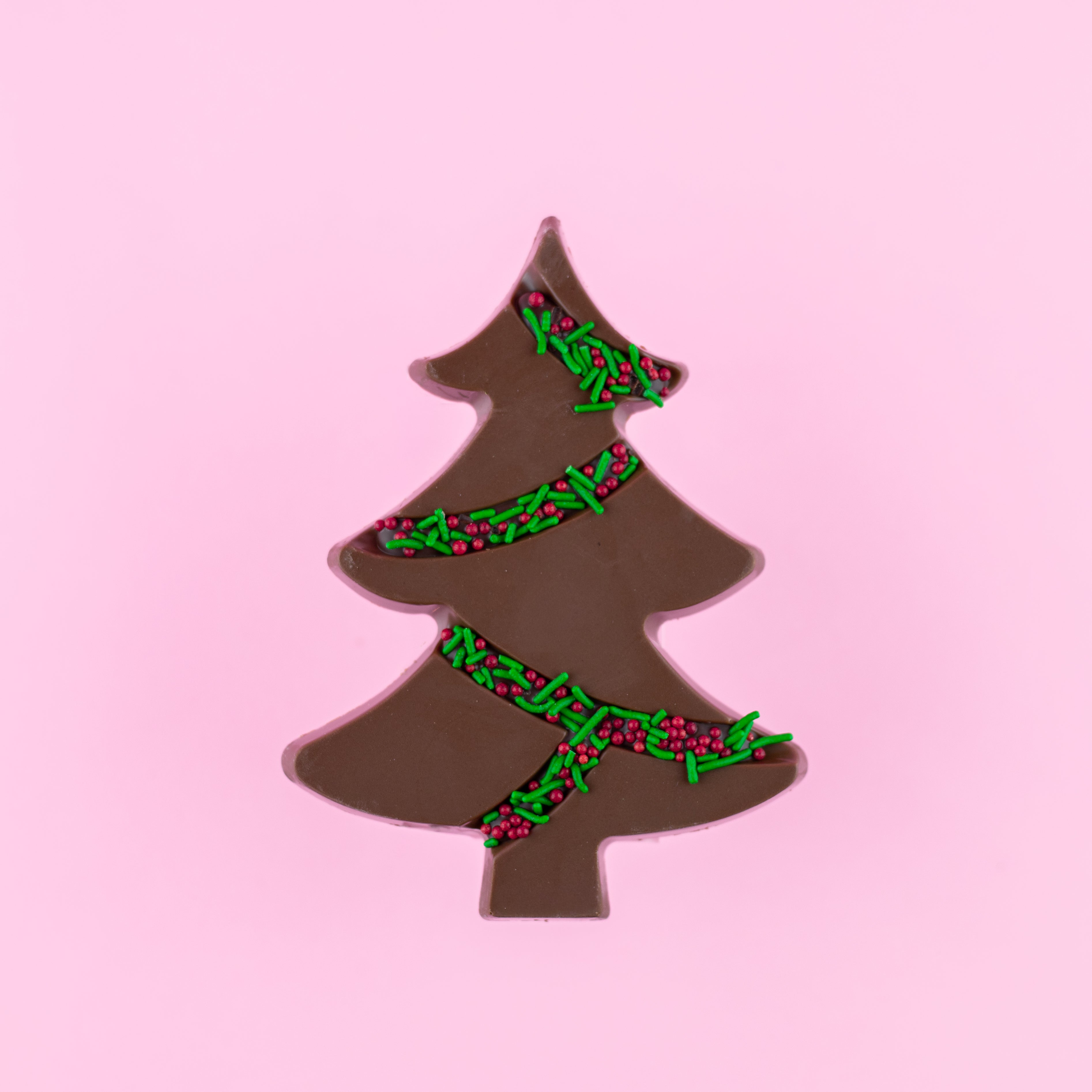 dark chocolate tree with green and red sprinkles on a pink background