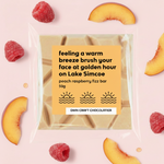 Load image into Gallery viewer, packaged chocolate bar with raspberries and peach slices on a light pink background
