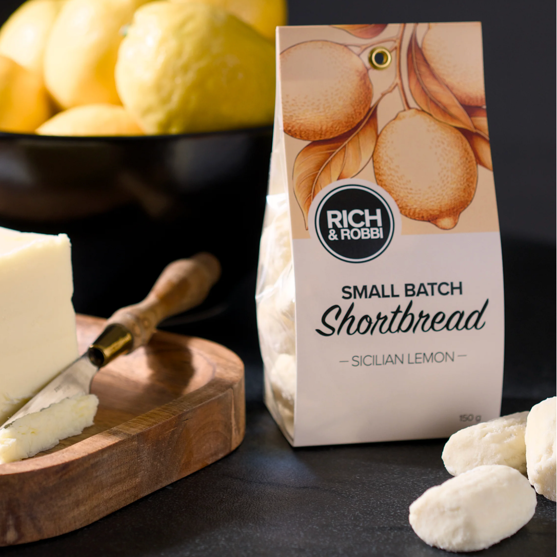 Rich & Robbie Sicilian Lemon Shortbread with lemons and shortbread cookies on a dark surface
