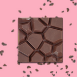 Load image into Gallery viewer, a ruby chocolate bar on a pink background with scattered cocoa nibs
