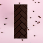 Load image into Gallery viewer, dark chocolate bar on a pink background with peppercorns in the background
