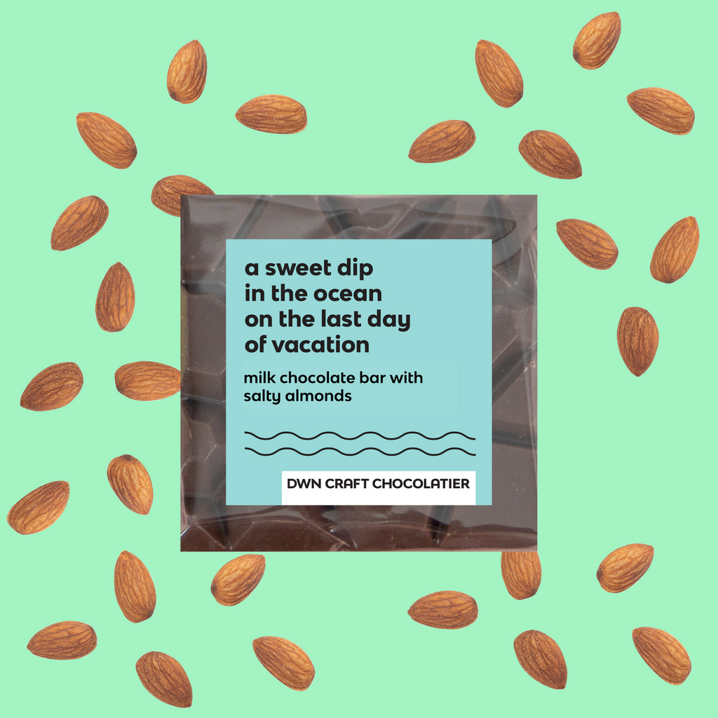 salty almond chocolate bar with a label on a light green background with scattered almonds