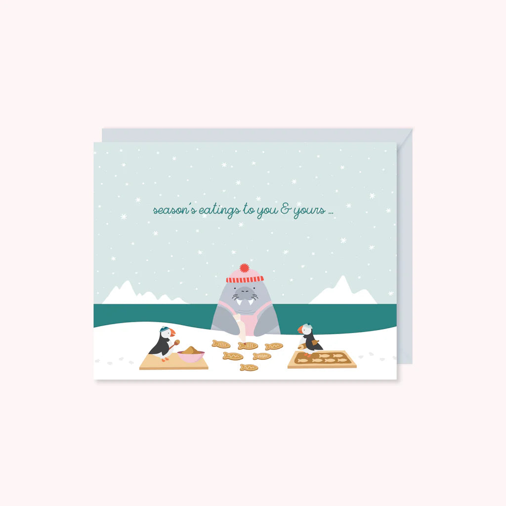 Greeting card with illustration of a hippo baking cookies in a snowy landscape, with text 'season's eatings to you & yours'.