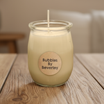Load image into Gallery viewer, small beige soy wax candle with a label that reads 'Bubbles by Beverley' placed on a wooden surface
