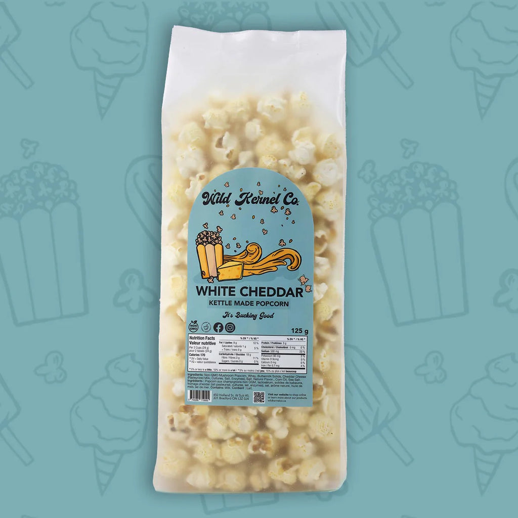 Bag of white cheddar kettle corn with a visible label on a teal background with popcorn icons.