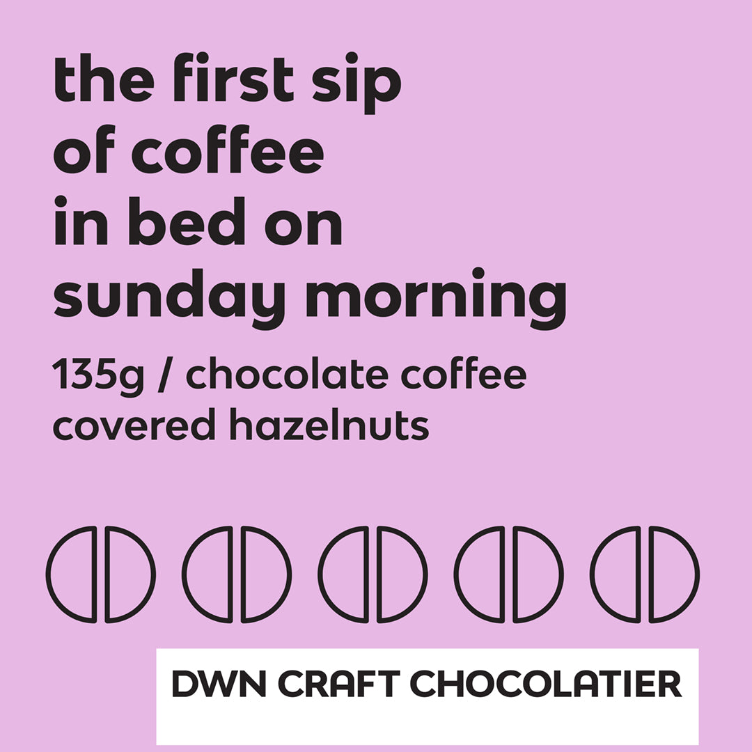 Chocolate coffee covered hazelnuts label with black text and a lavender background that reads, "the first sip of coffee in bed on sunday morning. 135g / chocolate coffee covered hazelnuts. DWN Craft Chocolatier"