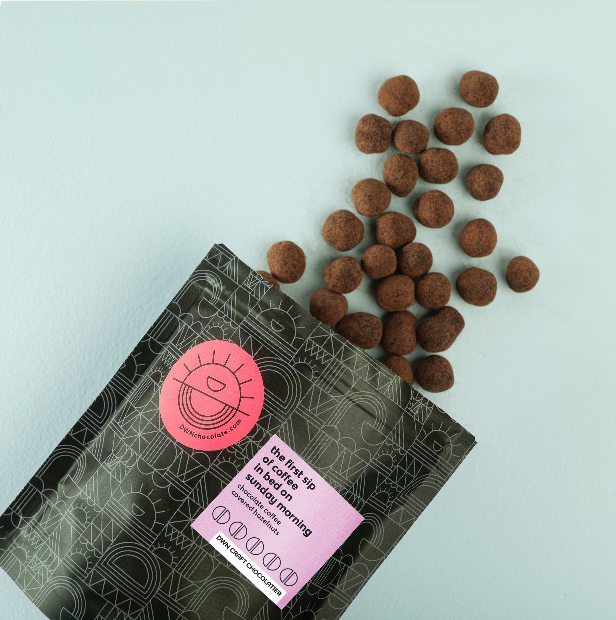 a pouch of chocolate-coffee hazelnuts fall out of the packaging onto a blue background
