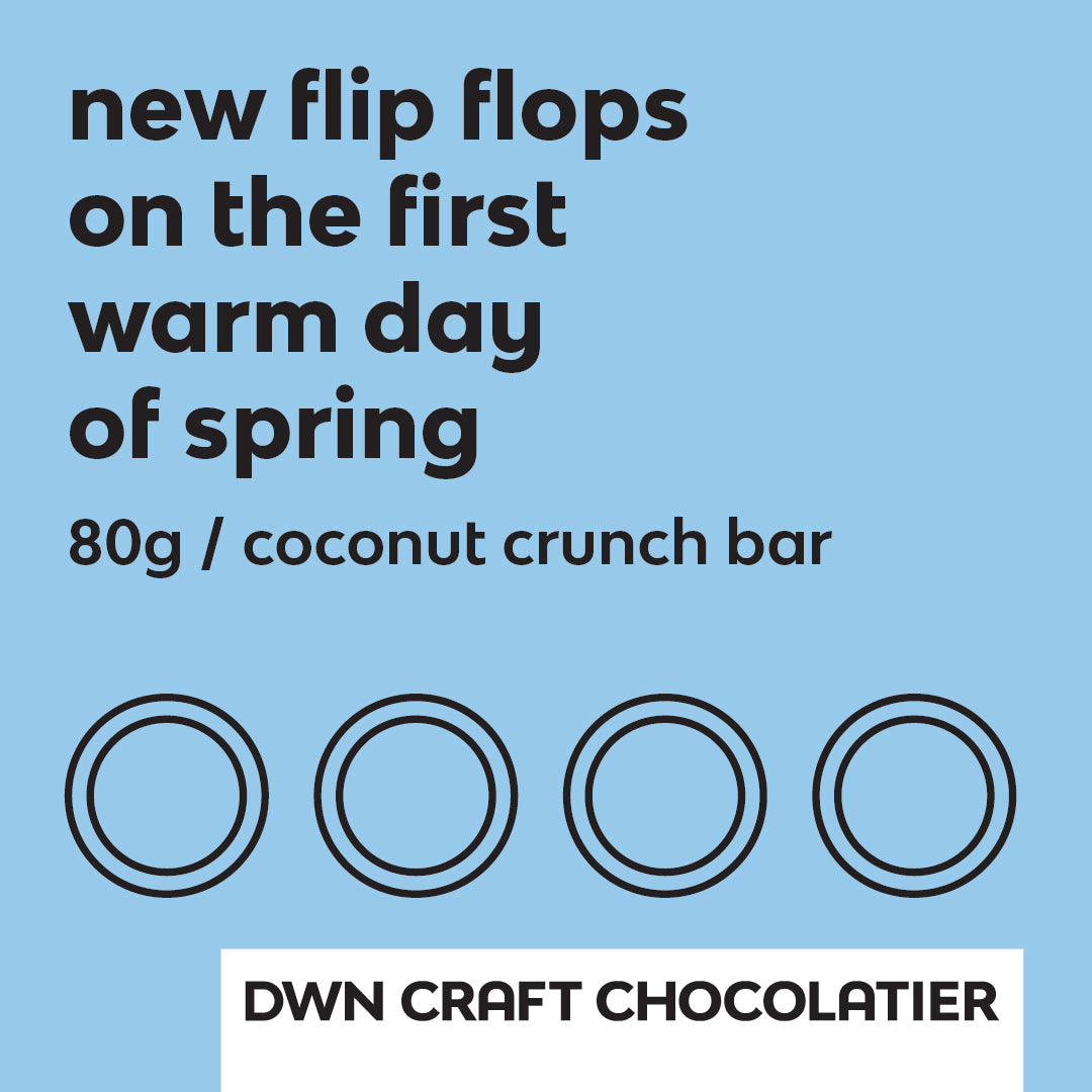 Label for coconut crunch bar has light blue background and black text that reads, "new flip flops on the first warm day of spring. 80g / coconut crunch bar. DWN Craft Chocolatier"