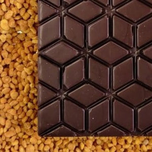 a close-up of the lilac dark chocolate bar lies on a bed of bee pollen