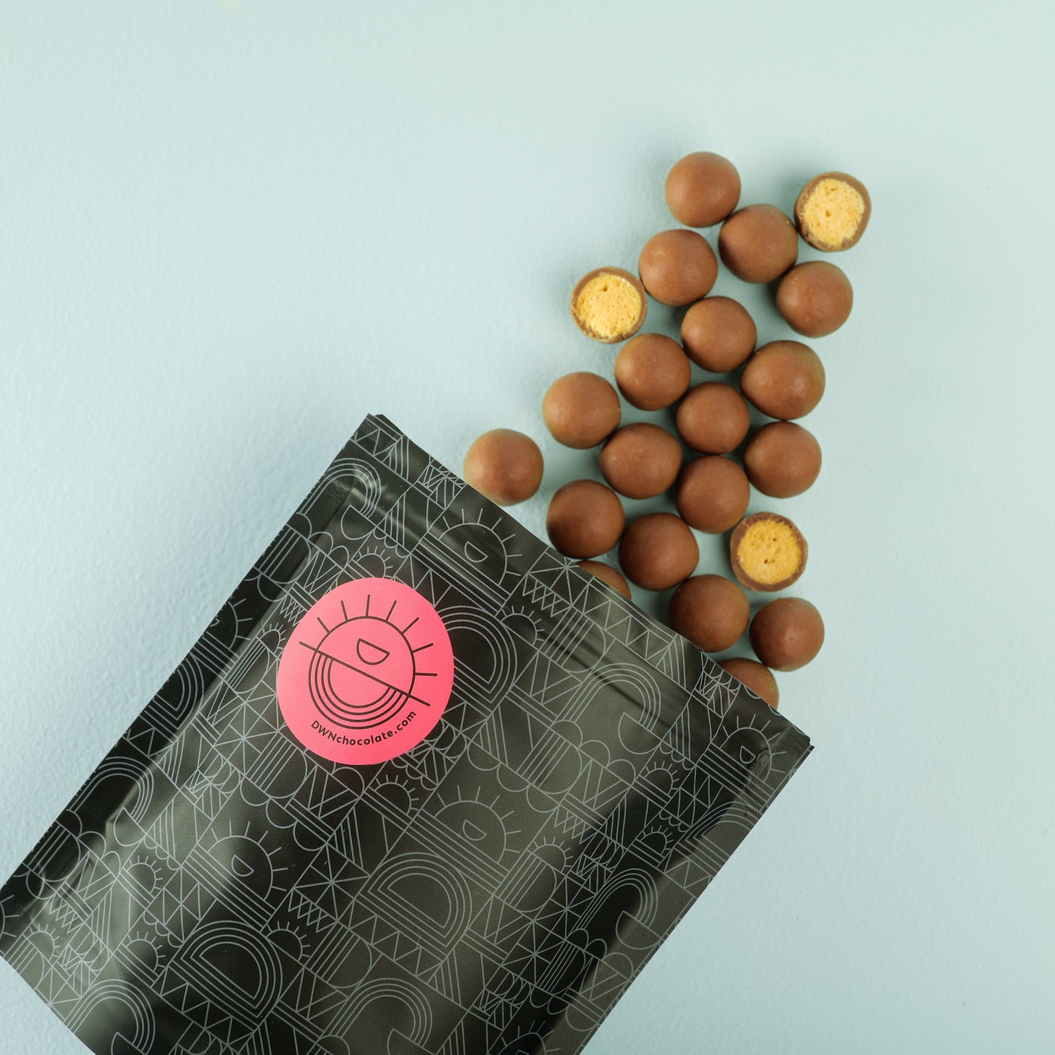 gingerbread malt balls spill out of a black DWN 