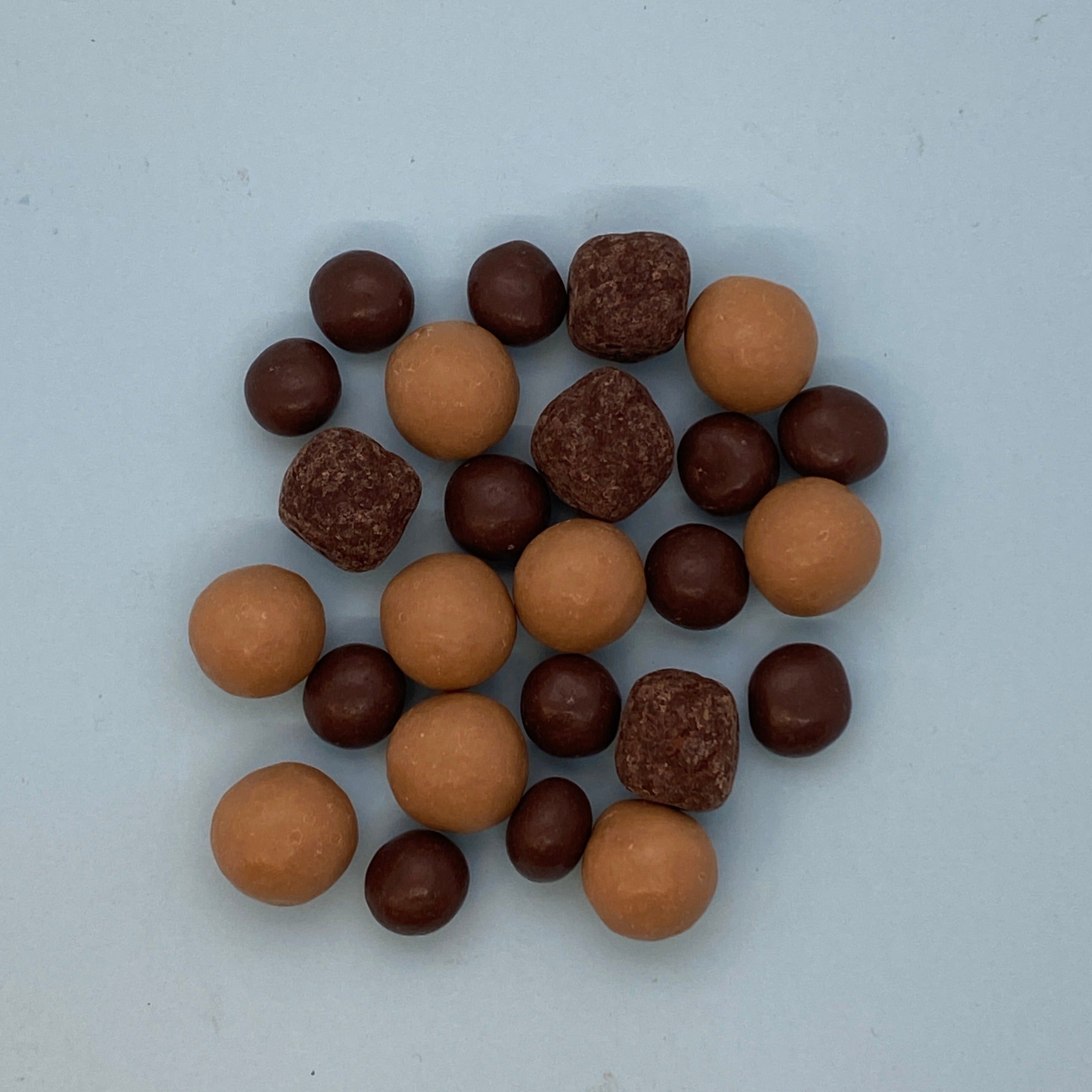 the contents of the chillin' mix on a blue background; nine light brown malt balls, twelve small dark brown pretzel balls and four pieces of caramel