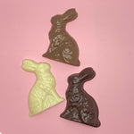 Load image into Gallery viewer, a dark chocolate, a milk chocolate and a white chocolate  rabbit on a pink background
