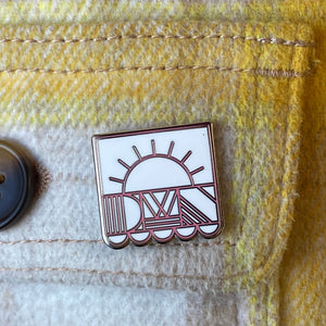 DWN enamel pin on a white and yellow plaid pocket