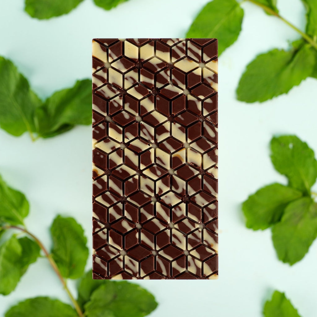 dark chocolate spearmint bar with whyte chocolate stripes on fresh mint leaves