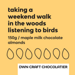 Load image into Gallery viewer, Maple milk chocolate almonds label with black text and a light orange background. The label reads, &quot;taking a weekend walk in the woods listening to birds. 150g / maple milk chocolate almonds. DWN Craft Chocolatier&quot;
