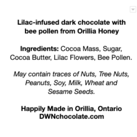 white background with black text that reads, "Lilac-infused dark chocolate with  bee pollen from Orillia Honey Ingredients: Cocoa Mass, Sugar,  Cocoa Butter, Lilac Flowers, Bee Pollen.  May contain traces of Nuts, Tree Nuts, Peanuts, Soy, Milk, Wheat and  Sesame Seeds.   Happily Made in Orillia, Ontario DWNchocolate.com"