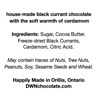 Black text on a white background reads, "house-made black currant chocolate  with the soft warmth of cardamom Ingredients: Sugar, Cocoa Butter,  Freeze-dried Black Currants,  Cardamom, Citric Acid.  May contain traces of Nuts, Tree Nuts,  Peanuts, Soy, Sesame Seeds and Wheat. Happily Made in Orillia, Ontario DWNchocolate.com"