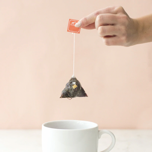 a tea bag being held over a tea cup