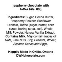 black text on a white background that reads, "raspberry chocolate with  toffee bits  80g Ingredients: Sugar, Cocoa Butter,  Raspberry Powder, Sunflower  Lecithin, Toffee (sugar, butter, corn  syrup, baking soda, salt), Whole  Milk Powder, Natural Vanilla Extract.  Contains Milk. May contain traces of  Nuts, Tree Nuts, Soy, Peanuts, Wheat,  Sesame Seeds and Eggs.  Happily Made in Orillia, Ontario DWNchocolate.com"