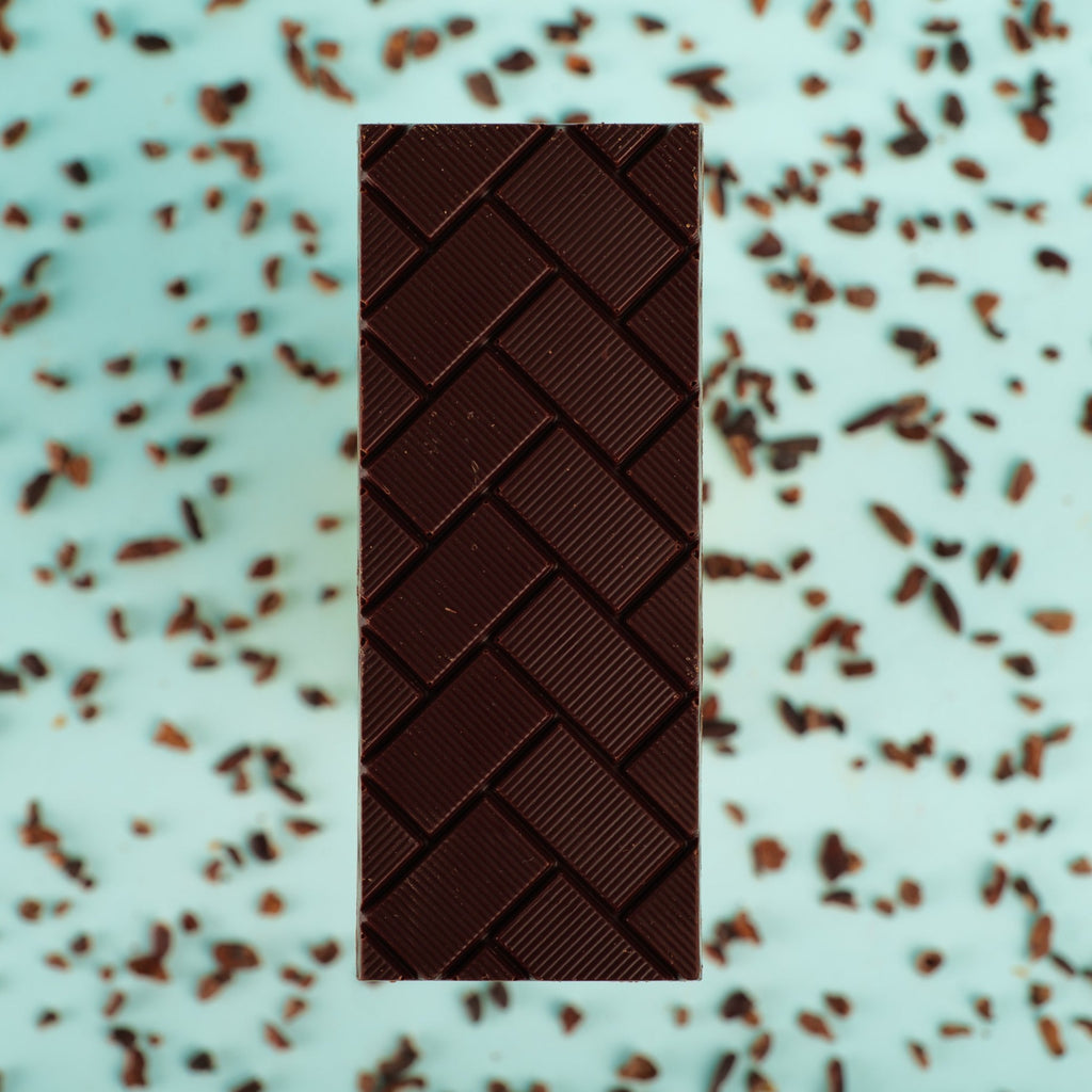 a sugar-free bar on a blue background surrounded by cocoa nibs