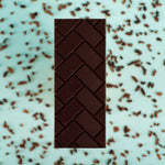 Load image into Gallery viewer, a sugar-free bar on a blue background surrounded by cocoa nibs
