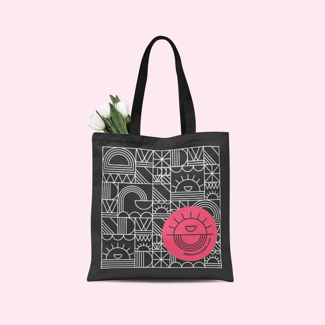tulips poking out of a black tote bag on a light pink background